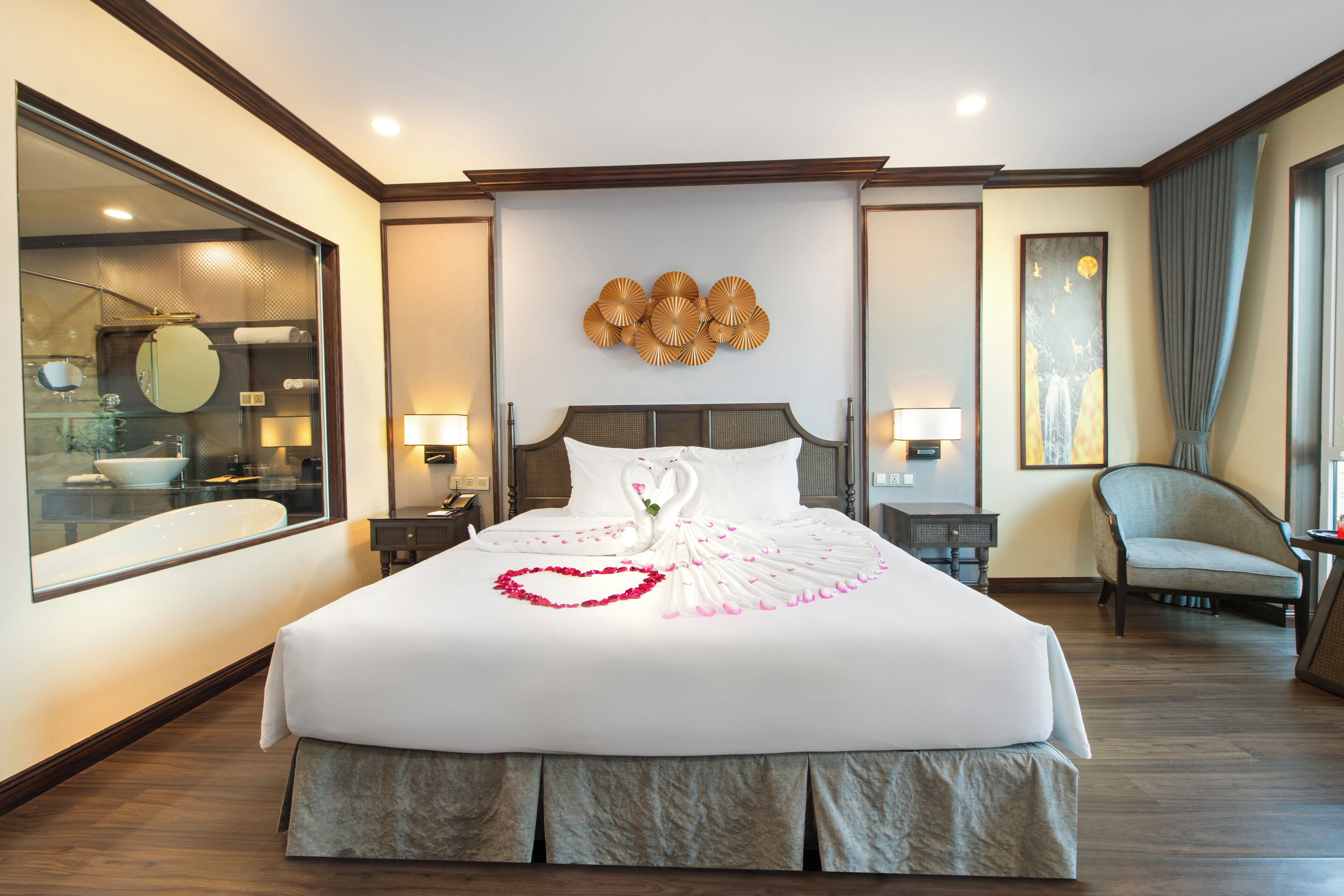 A hotel room with a large bed, a mirror, a nightstand, a chair, and a painting on the wall.