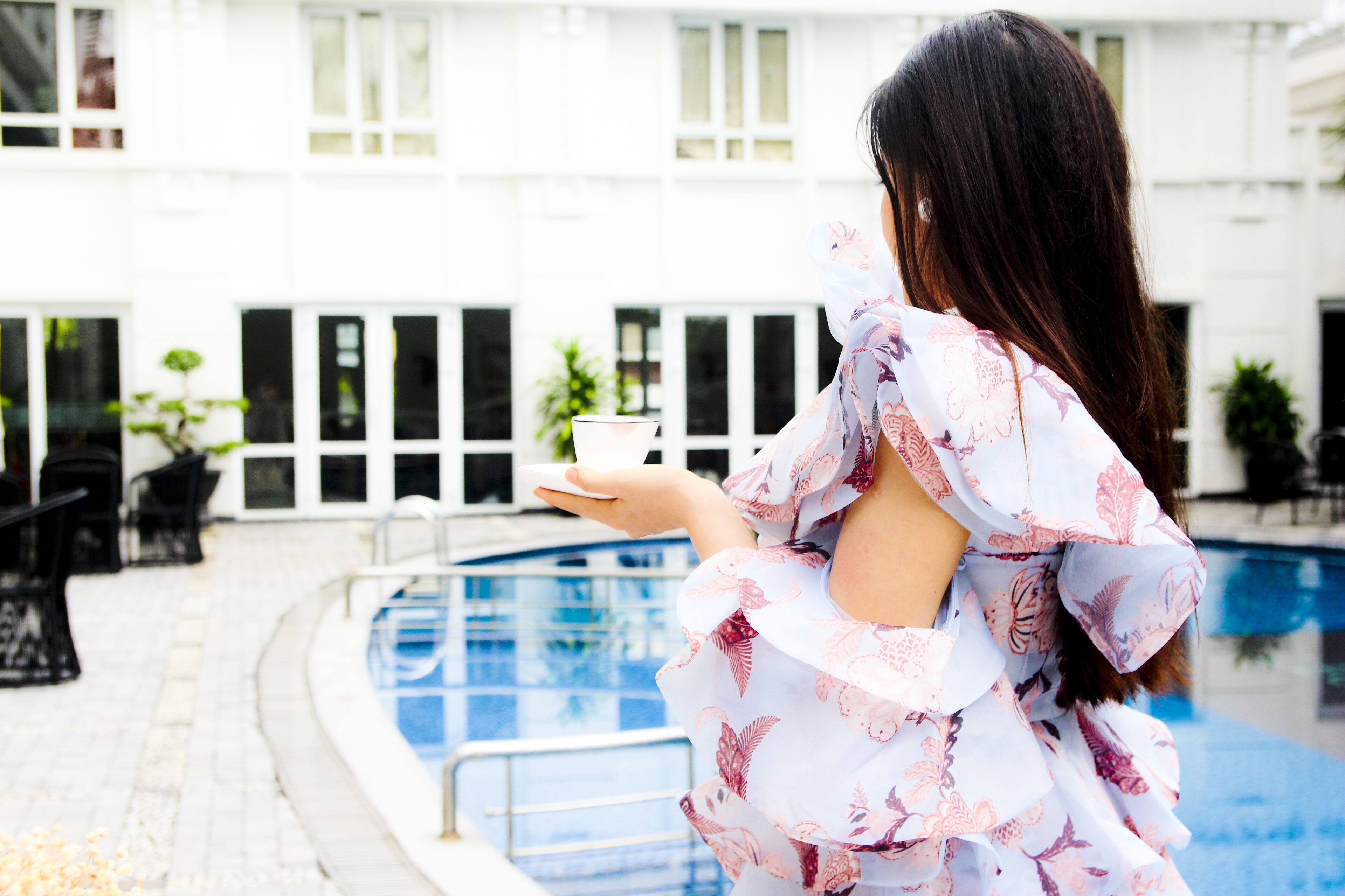 A person standing by a pool with a building in the background.