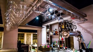 A bar area with a polished bar counter, hanging wine glasses, and a variety of bottles. - Hotel Oriental Aster - Mumbai International Airport (Mumbai)