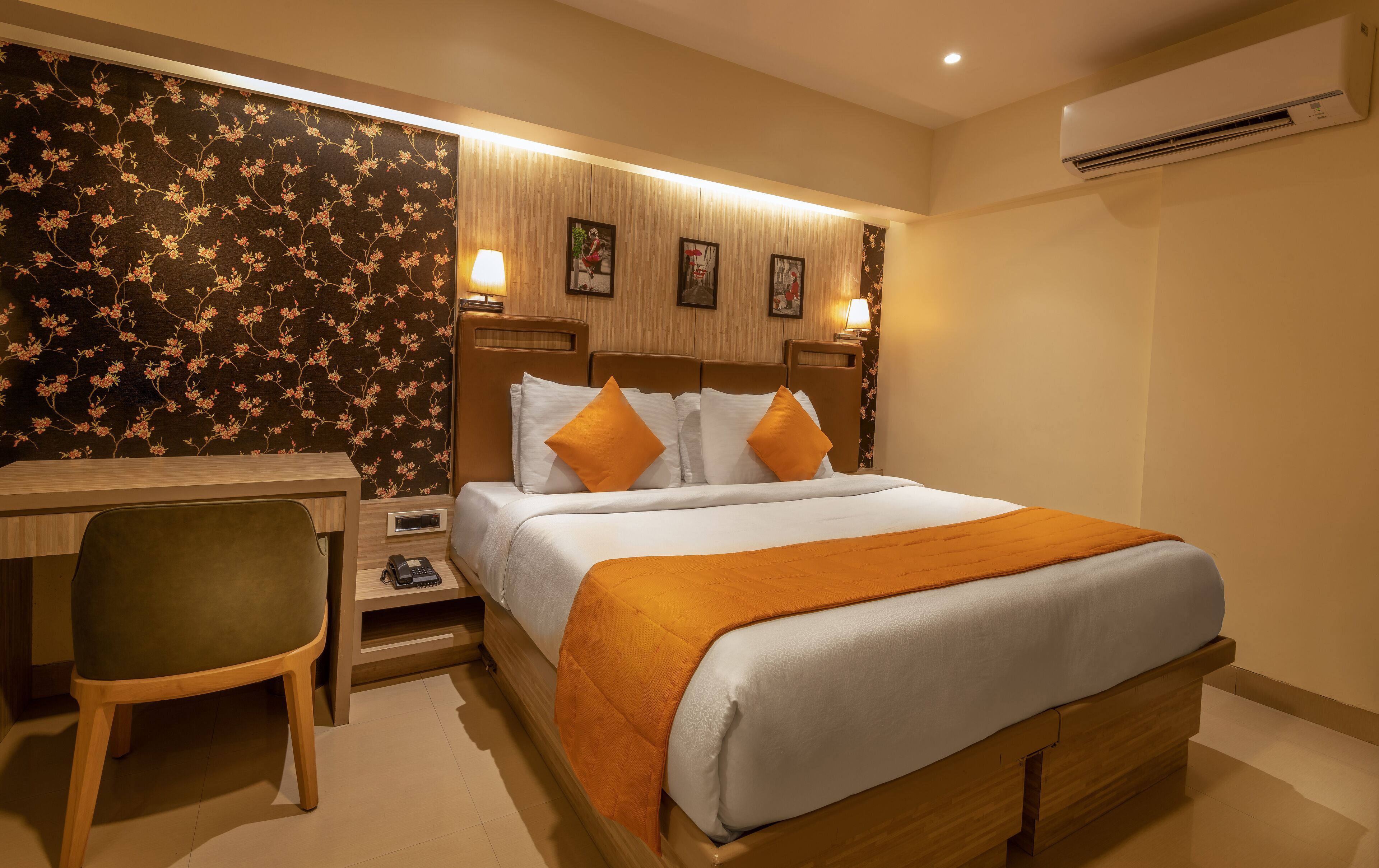 Habitación de hotel con cama, escritorio, silla y unidad de aire acondicionado en la pared.