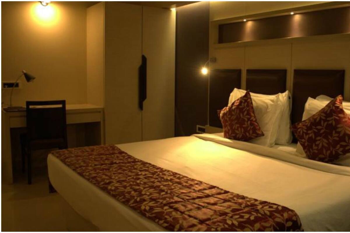A hotel room with a large bed, two bedside tables, a desk, and a chair.