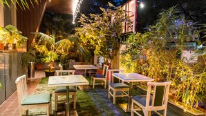 An outdoor patio area with tables and chairs, surrounded by lush greenery and potted plants. - Hotel Oriental Aster - Mumbai International Airport (Mumbai)