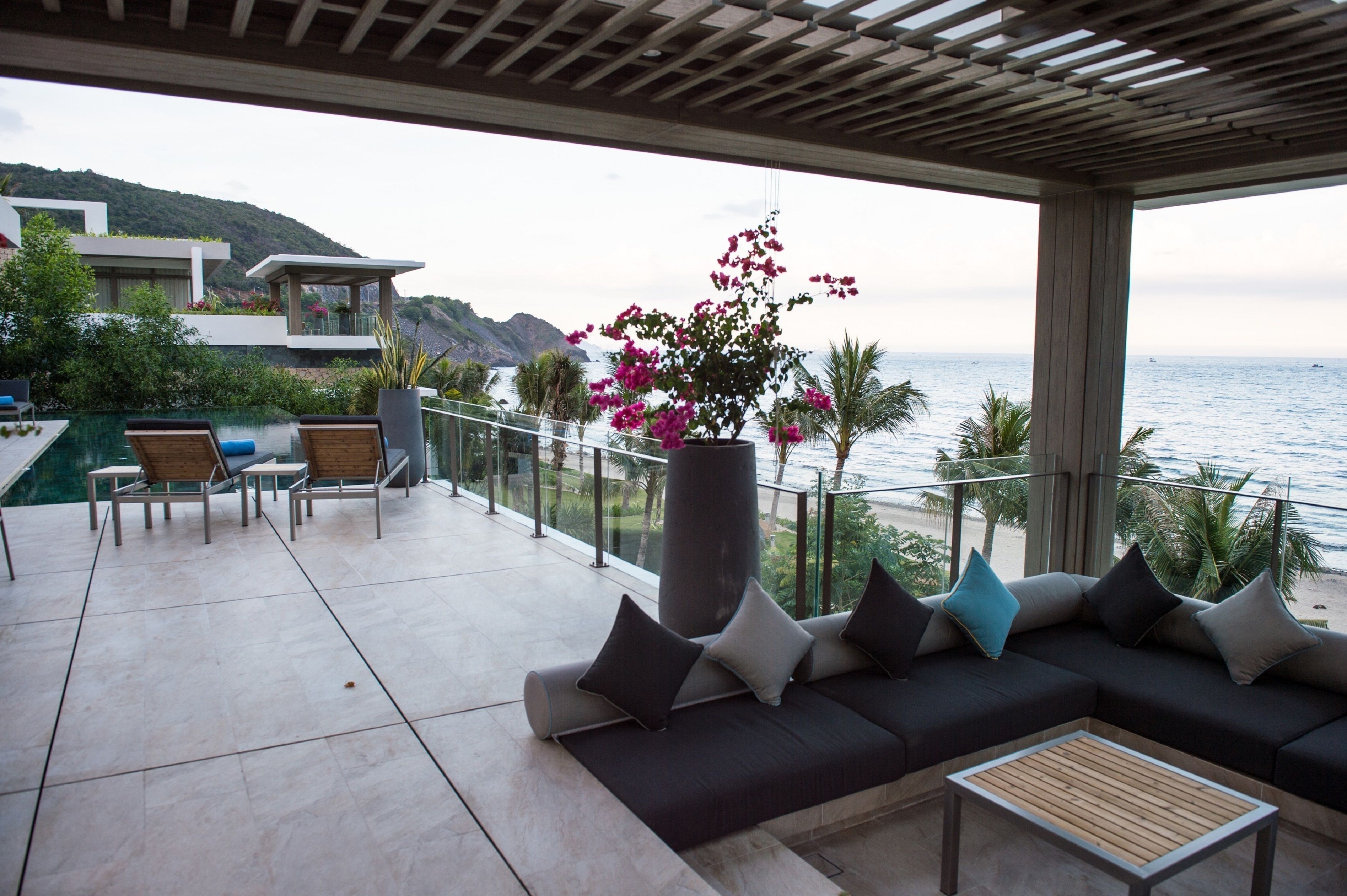 A modern outdoor lounge area with a pool, seating, and a view of the sea.
