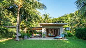 A modern house with a covered patio, a hammock, and a seating area with cushions.