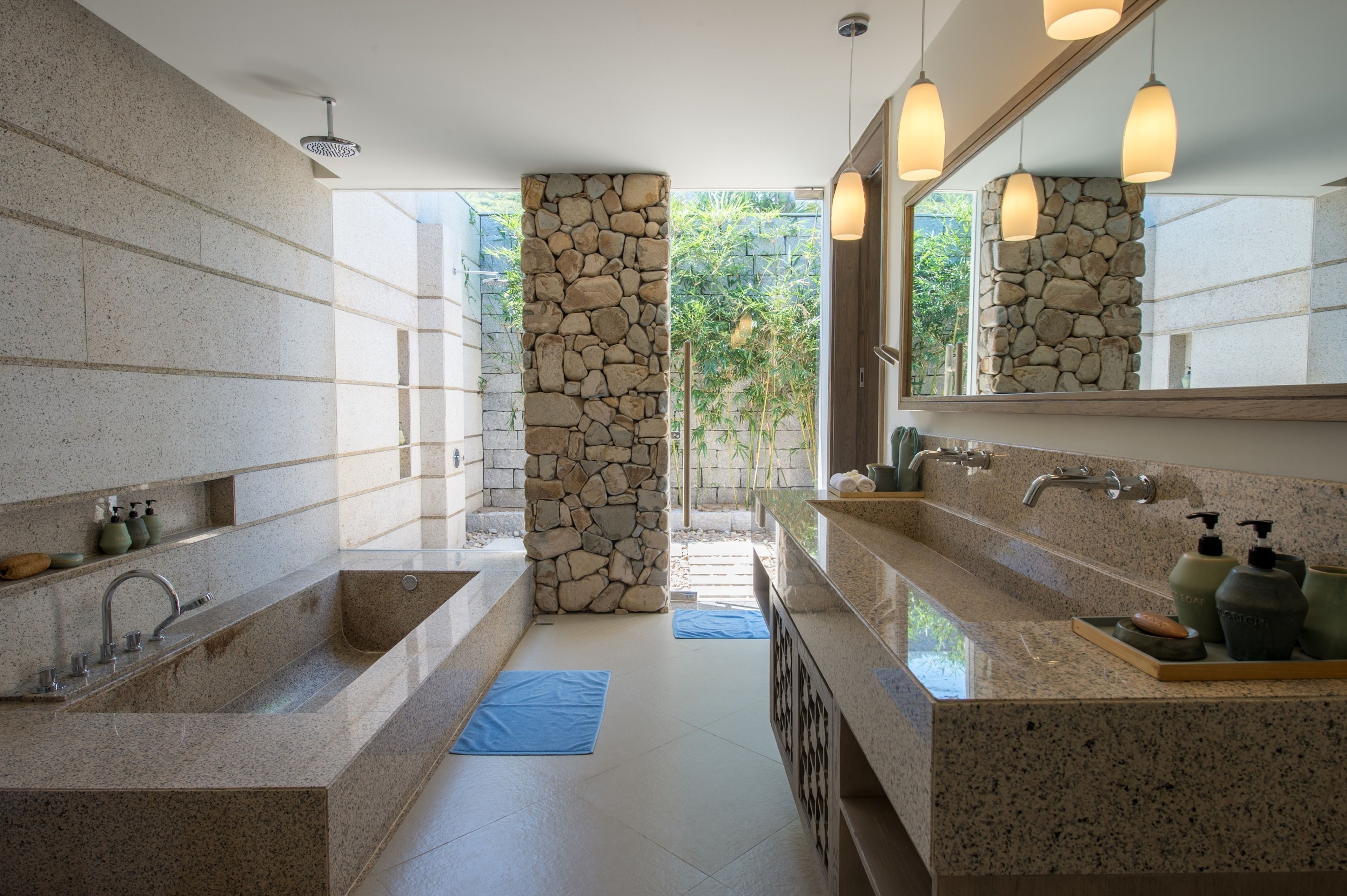A modern bathroom with a stone accent wall, dual sinks, and a large mirror.