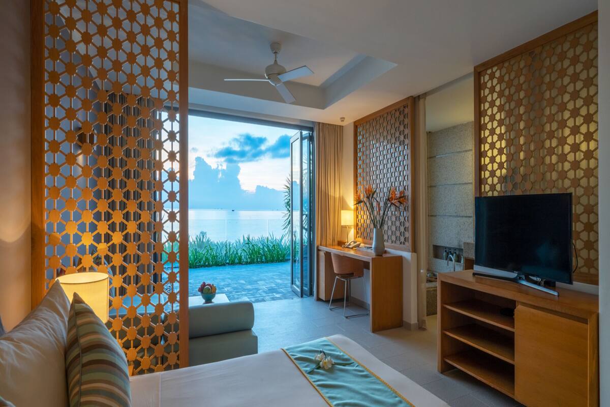 A hotel room with a bed, a desk, a television, and a view of the outdoors.