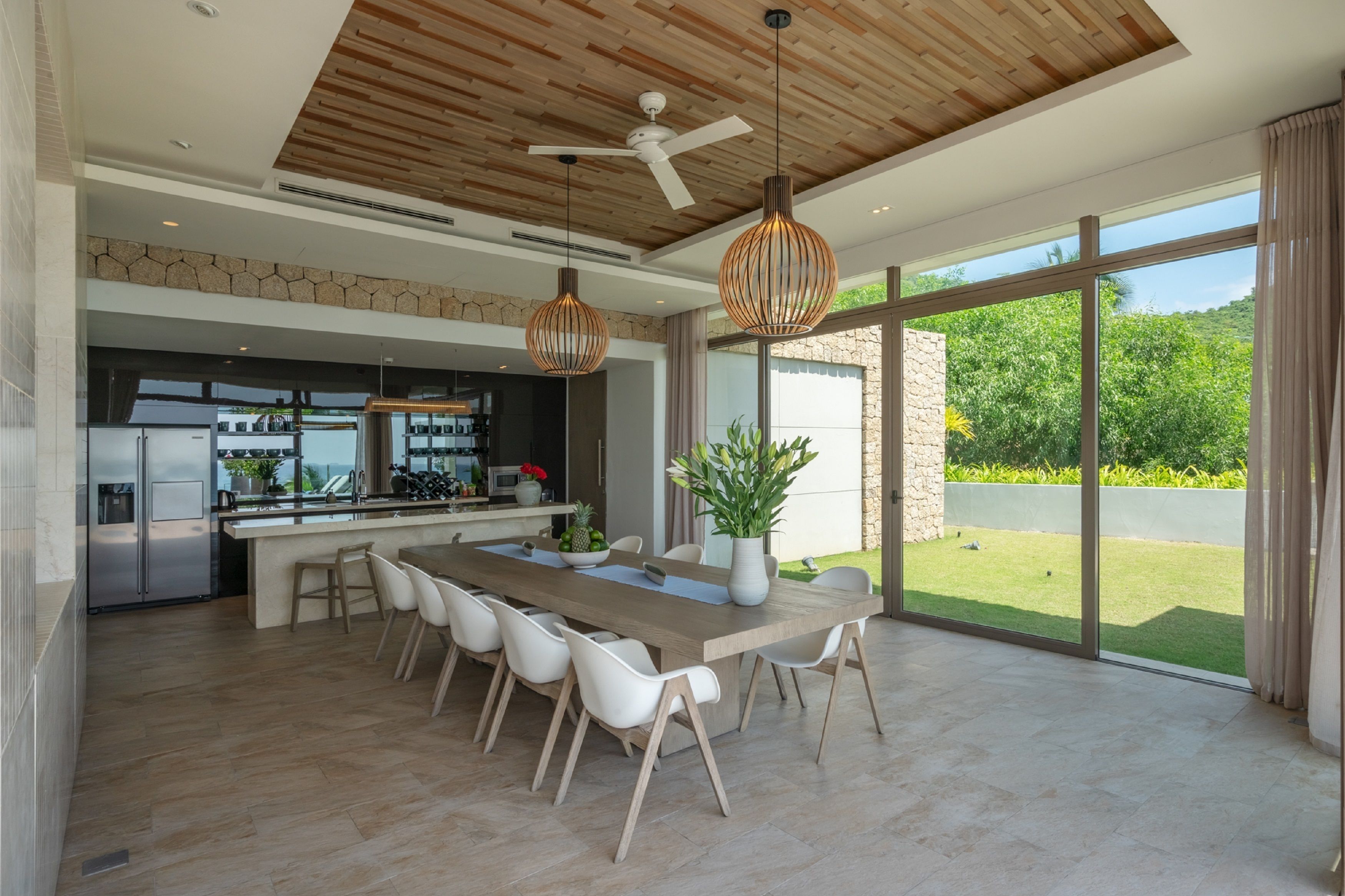 Una cocina moderna con una isla central, ventanas amplias y un ventilador de techo.