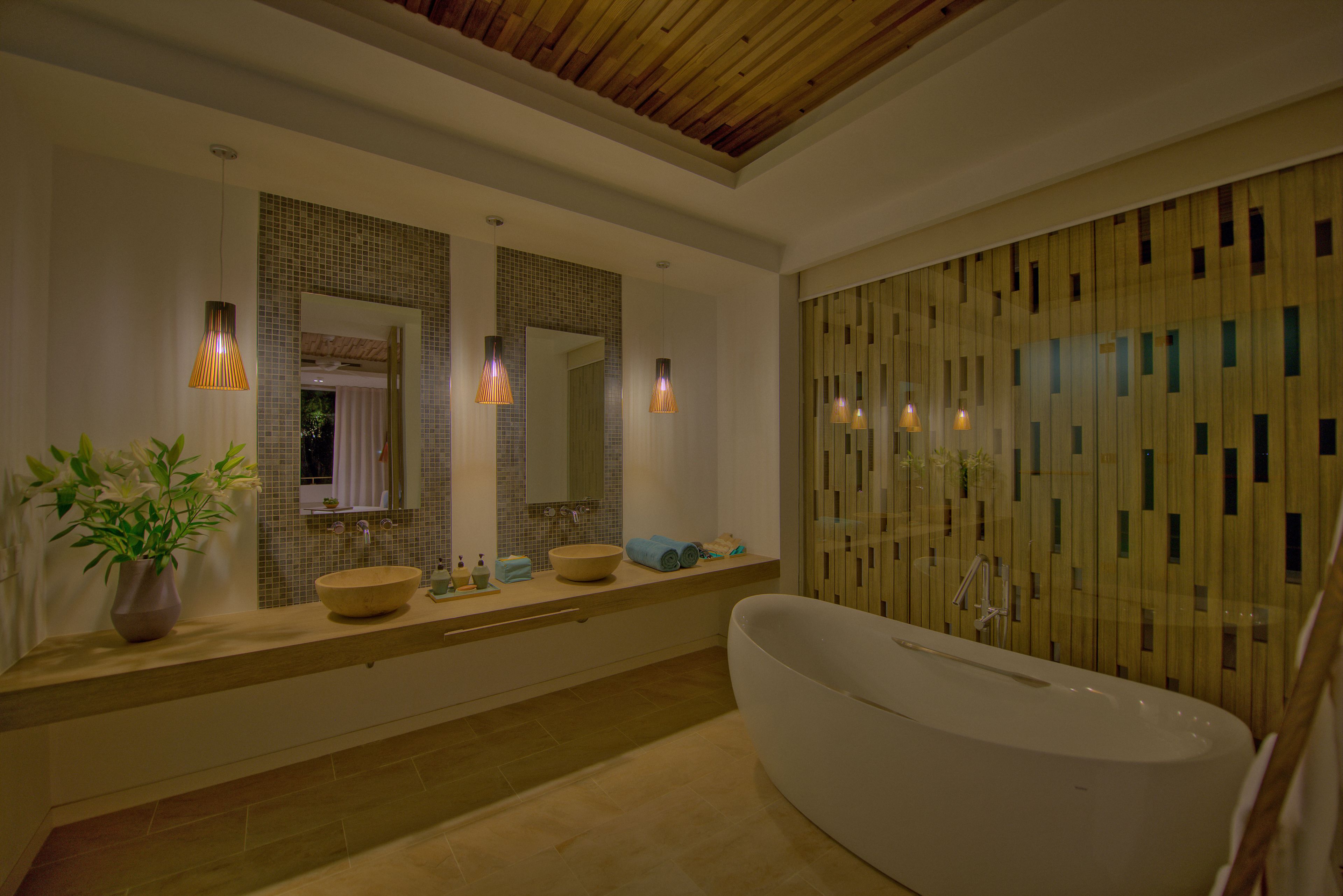 A modern bathroom with a freestanding bathtub, a large mirror, and a wooden panel wall.
