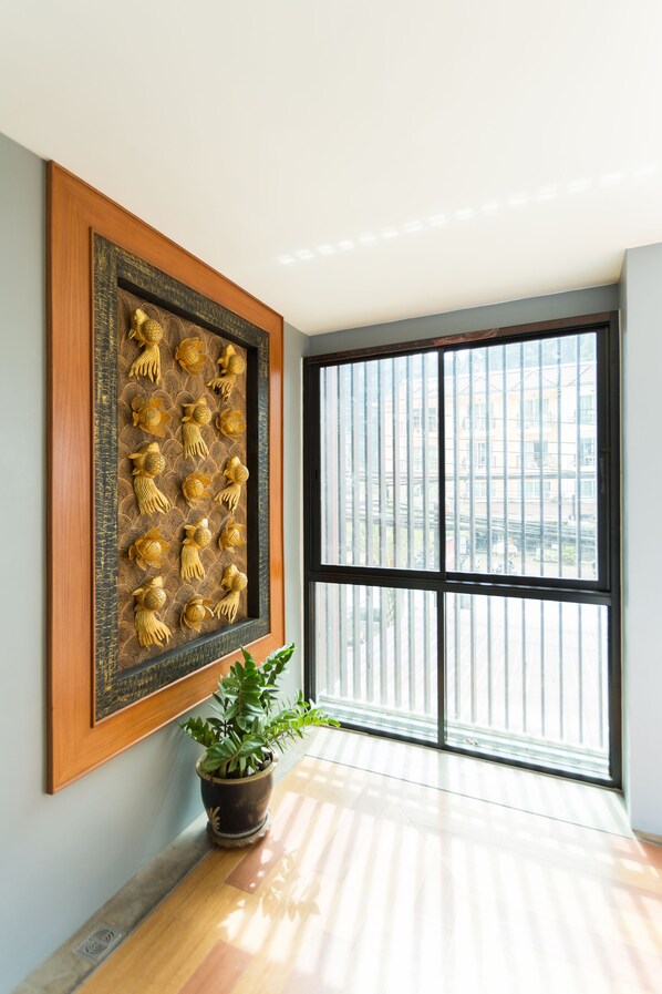 A room with a large window, a framed wall decoration, and a potted plant. - Phranang Place Hotel (Krabi)