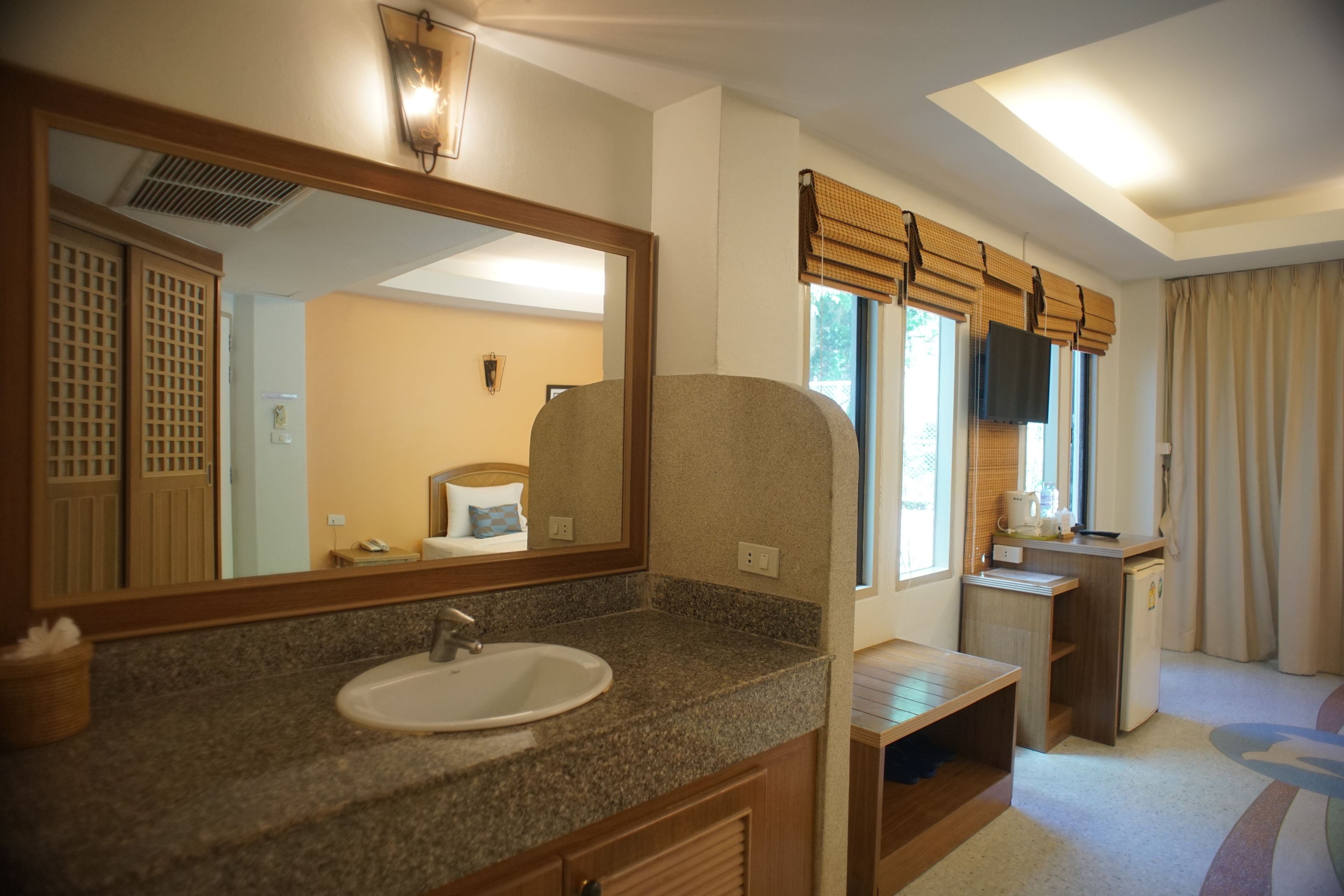 A bathroom with a granite countertop sink, a large mirror, and a window with blinds.