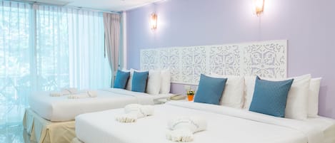 A hotel room with two beds, a large window with sheer curtains, a decorative headboard, and a wall-mounted light fixture.