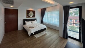 Un dormitorio moderno con cama, una lámpara en el techo, una ventana con cortinas y vistas a edificios.