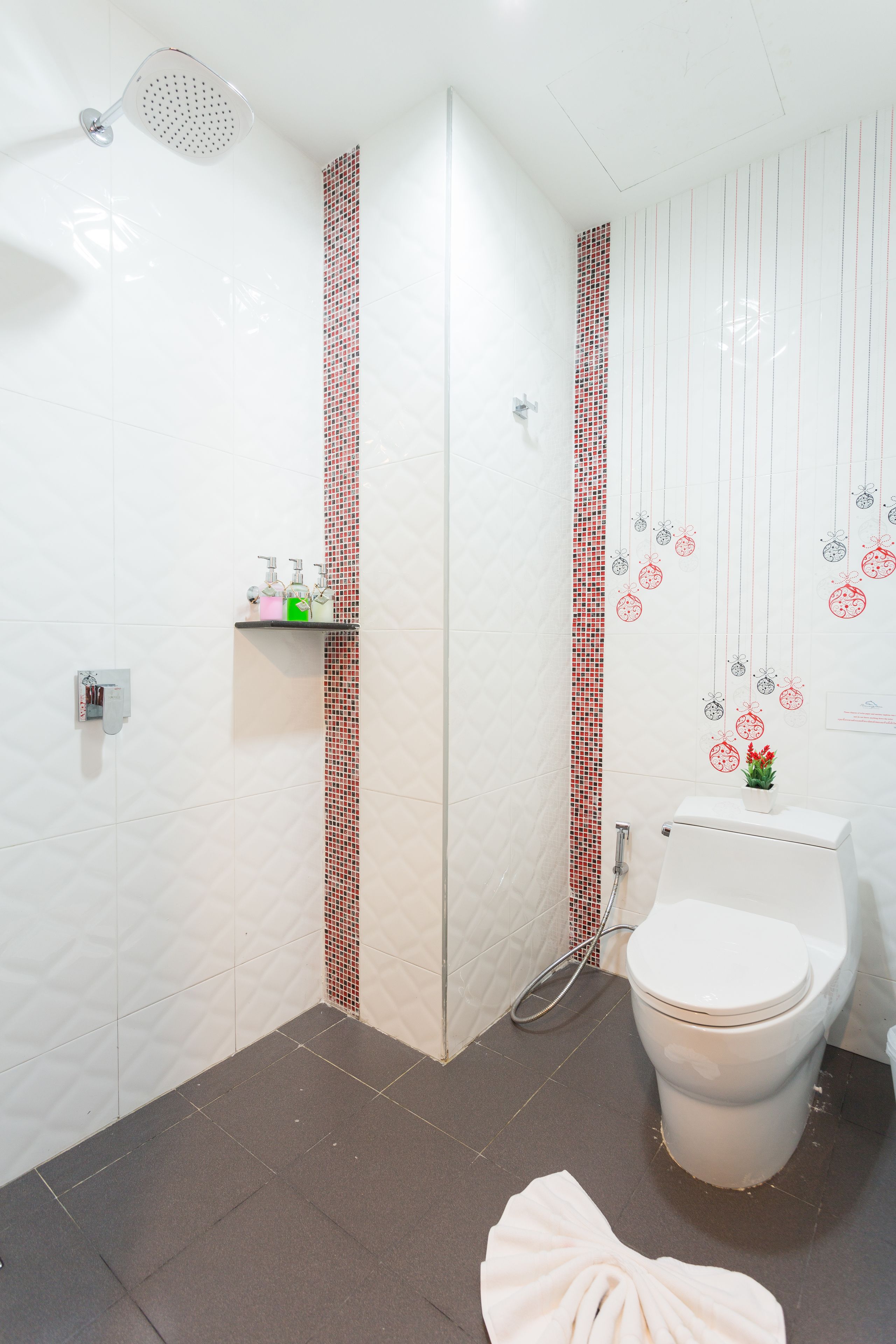 A bathroom with a shower, toilet, and a towel on the floor.