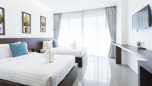 Habitación de hotel moderna con dos camas, un televisor de pantalla plana, una mesita pequeña y un ventanal grande con cortinas.
