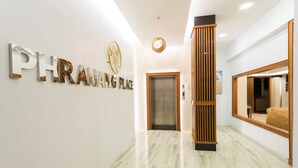 Un pasillo moderno con piso de mármol, una recepción y un letrero que dice "PHRAING PLACE".