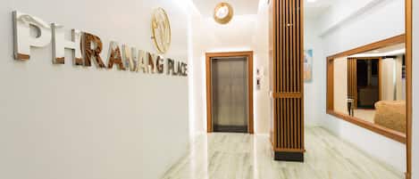 A modern hallway with a marble floor, a reception desk, and a sign that reads "PHRAING PLACE".