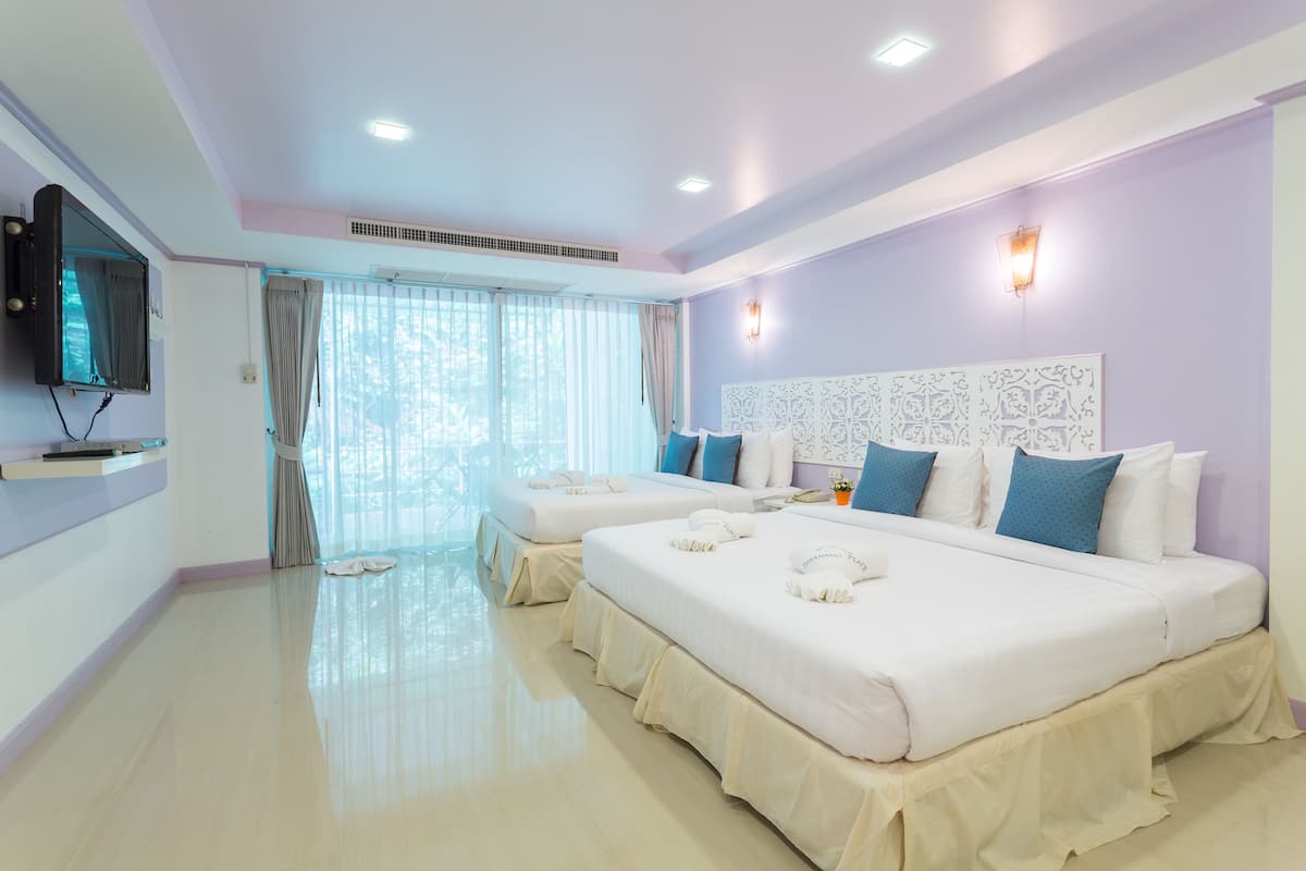 A hotel room with two beds, a television, a large window with curtains, and a decorative wall panel.