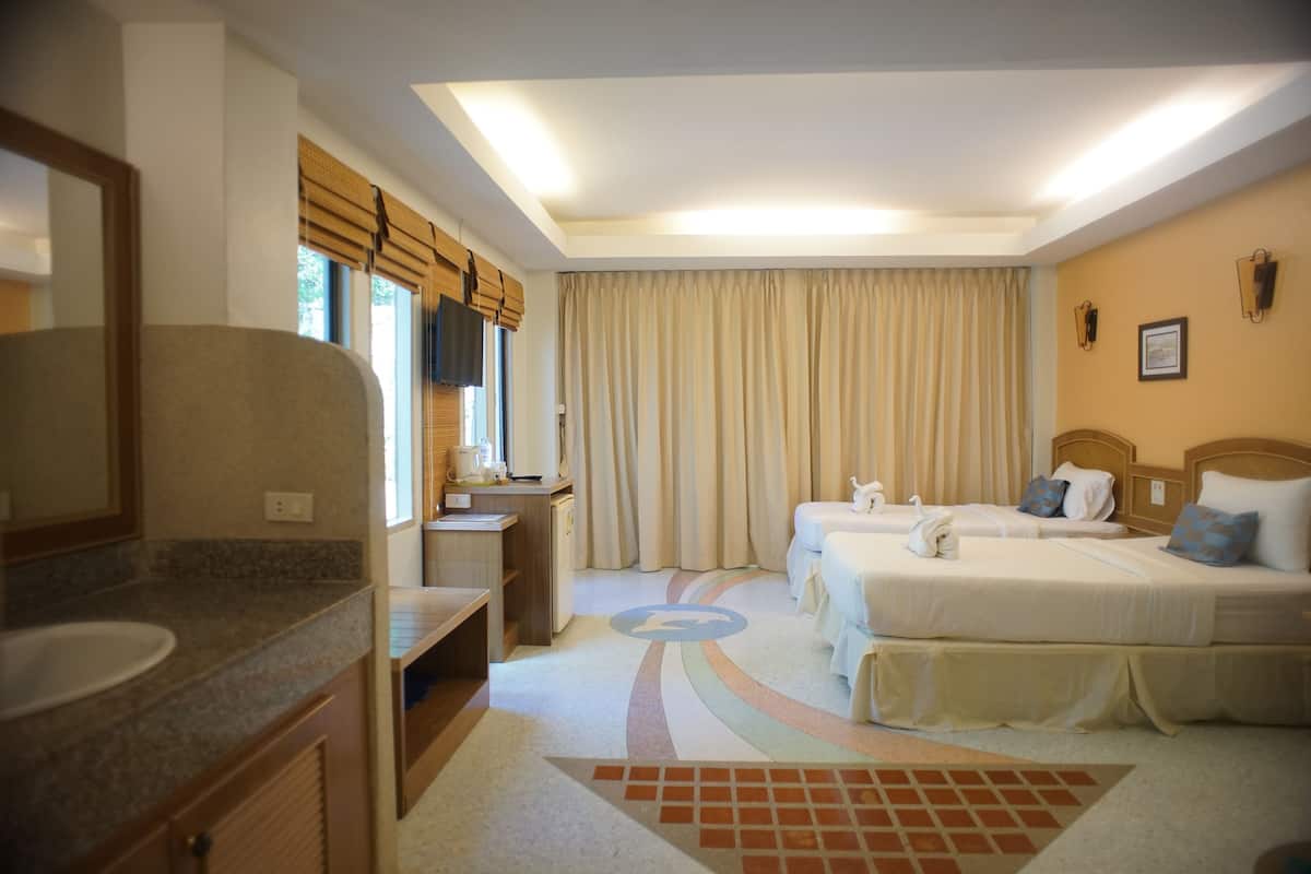 A hotel room with a bed, two bedside tables, a desk, a chair, a window with curtains, and a bathroom with a sink and mirror.