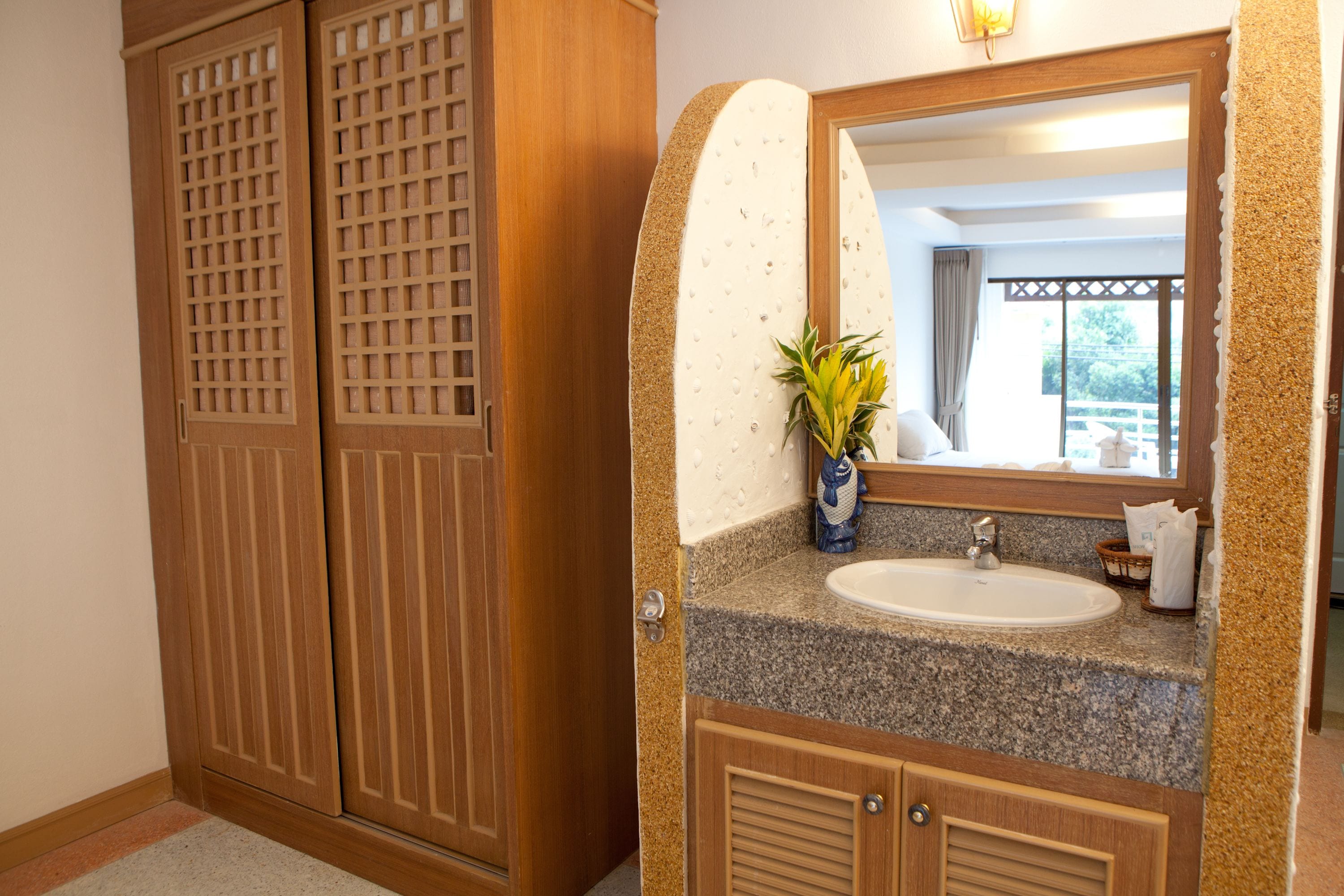 A bathroom with a granite countertop, a sink, a mirror, and a potted plant.