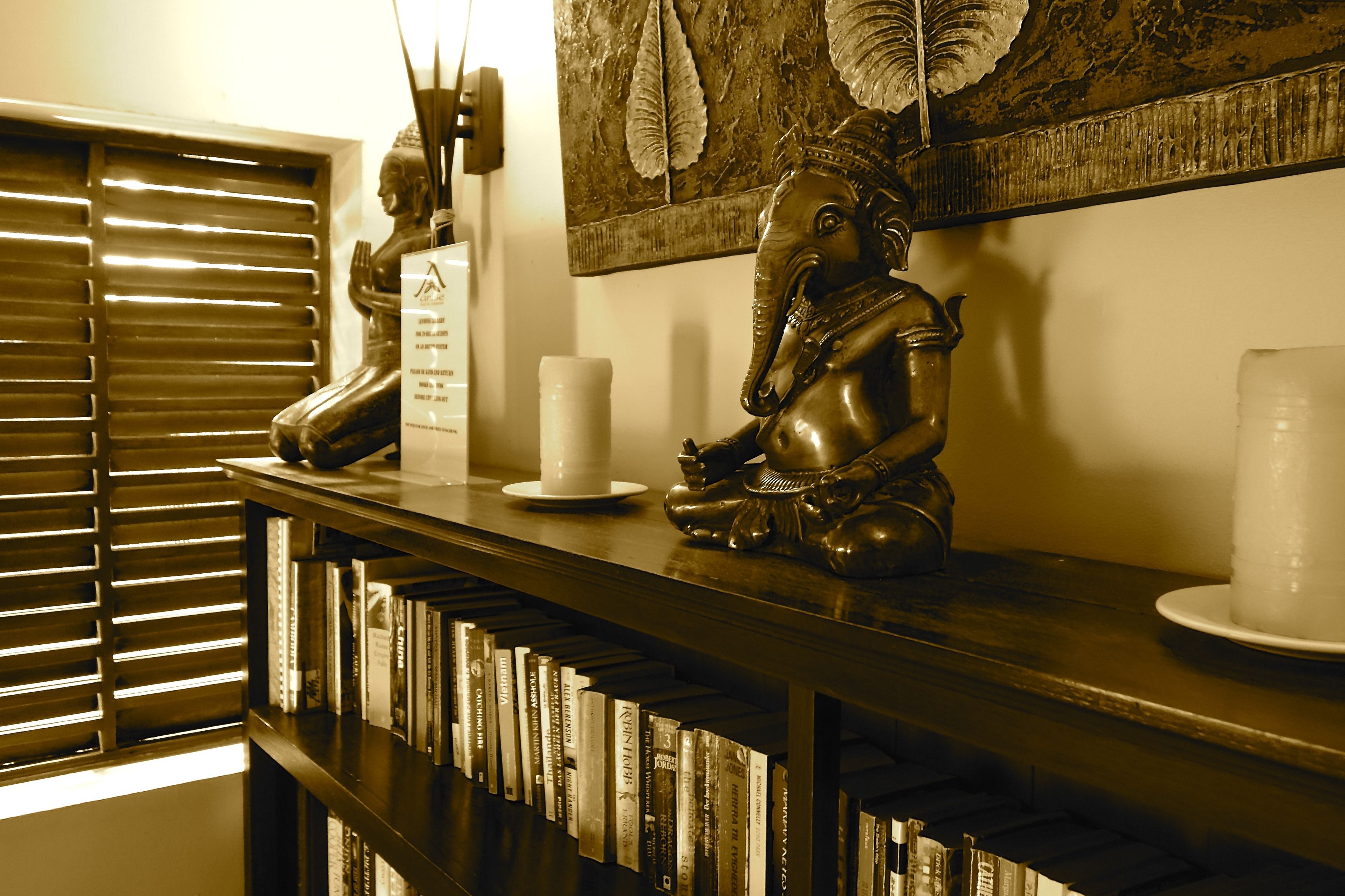 A reception desk with a statue, a framed artwork, and a row of books.