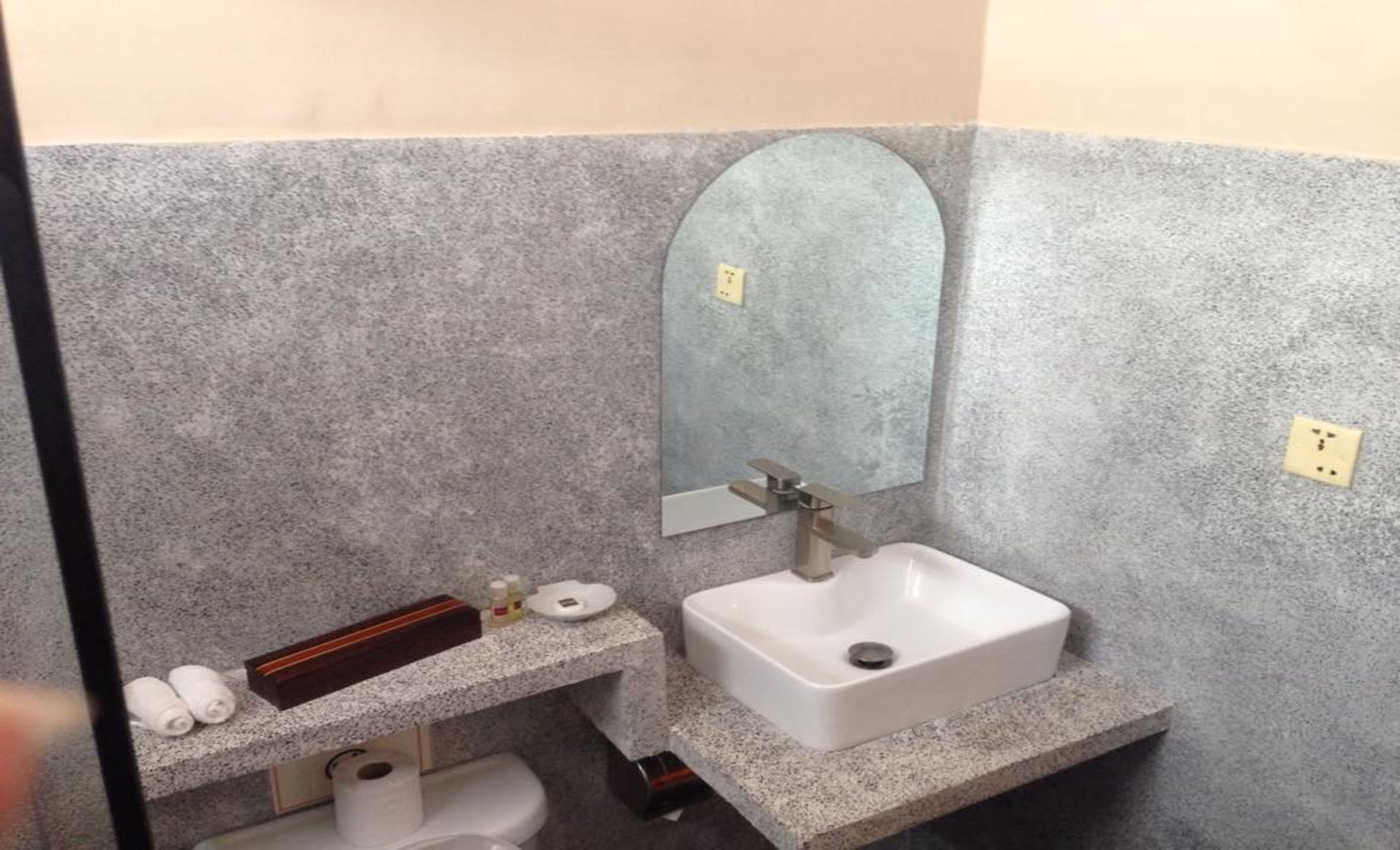A small, compact bathroom with a white sink, a mirror, and a towel dispenser.