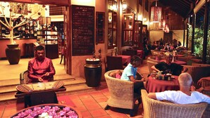 A restaurant with wicker furniture, a bar area, and a menu board. - Anise Hotel & Restaurant (Phnom Penh)