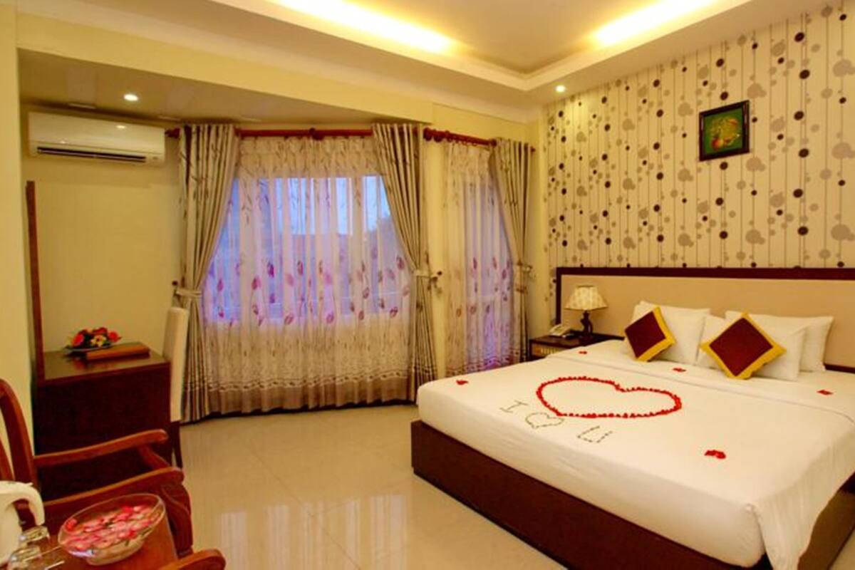 Une chambre d’hôtel avec un grand lit, une table de chevet, une chaise et un mur orné d’un motif décoratif.