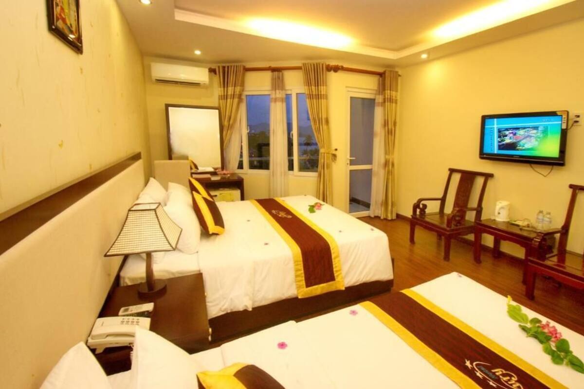 Une chambre d’hôtel avec deux lits, un bureau, une chaise, une télévision et une fenêtre avec des rideaux.