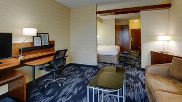 A hotel room with a desk, chair, bed, and a sofa.