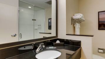 A modern bathroom with a glass sink, a large mirror, and a towel rack.