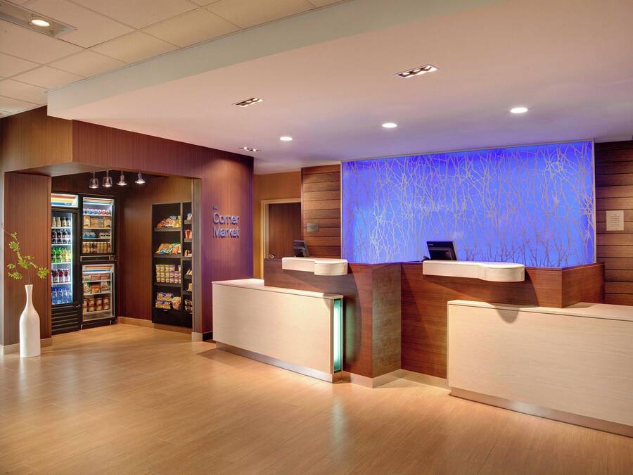 A hotel reception area with a modern design, including a reception desk, a digital screen, and a vending machine.