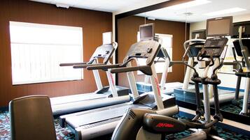 Un gimnasio con cintas de correr, elípticas y una bicicleta estática.