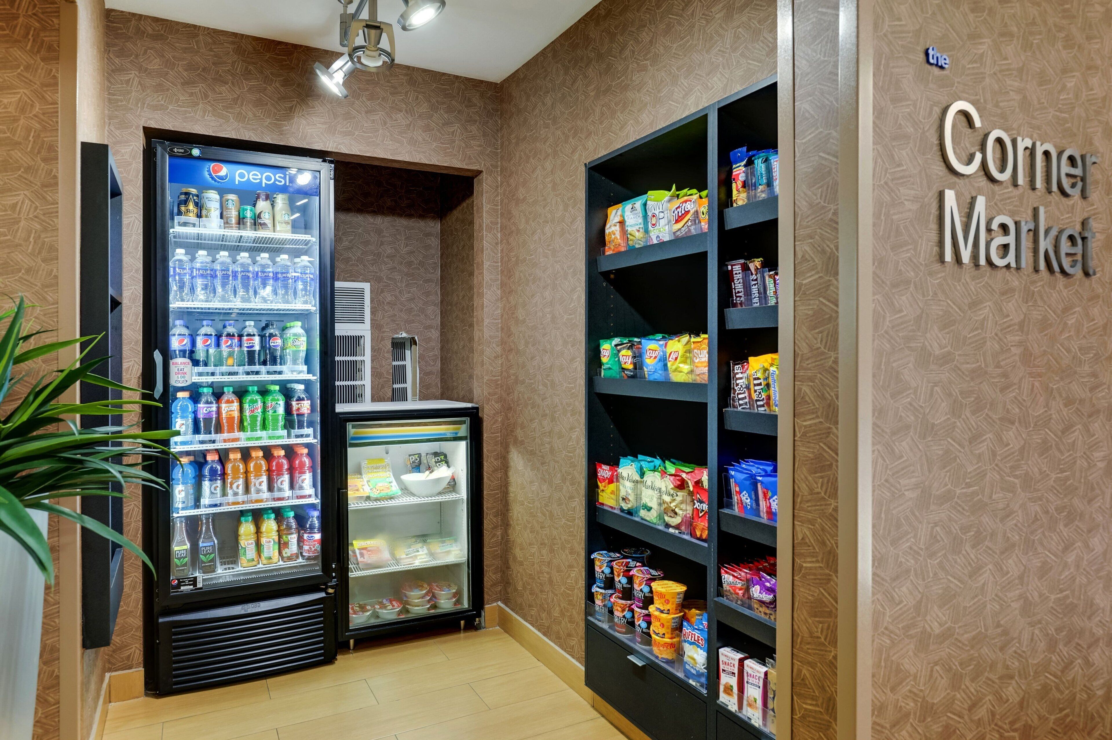 Un mercado de barrio con un refrigerador de Pepsi y estantes llenos de botanas y bebidas.