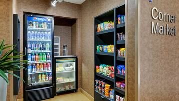 Un mercado de barrio con un refrigerador de Pepsi y estantes llenos de botanas y bebidas.