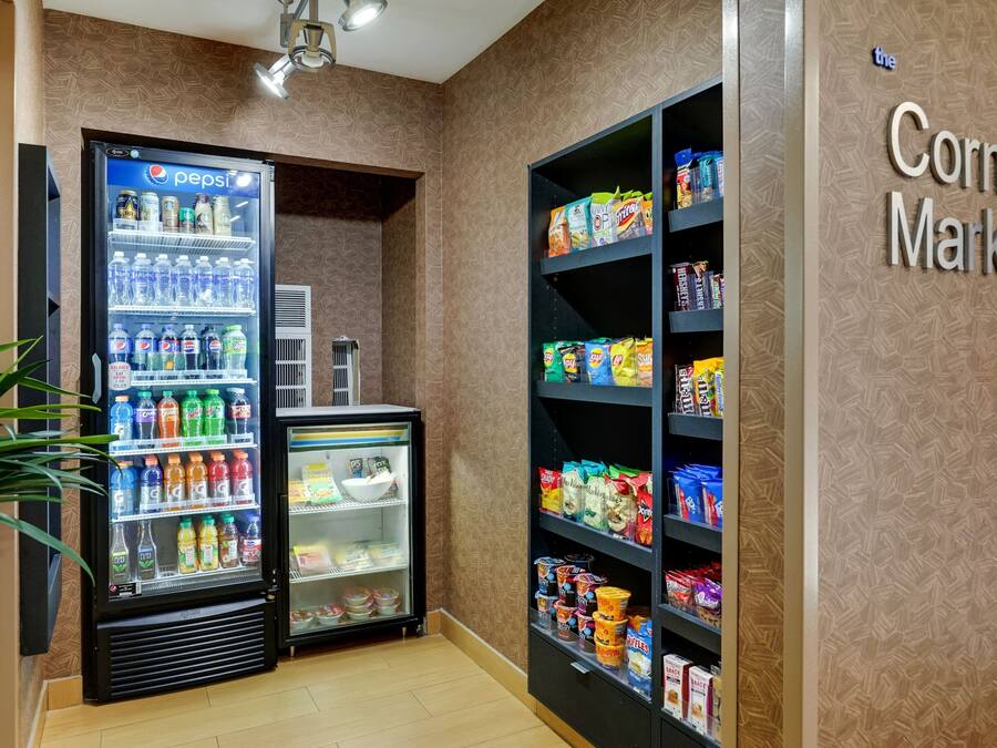 Un mercado de barrio con un refrigerador de Pepsi y estantes llenos de botanas y bebidas.