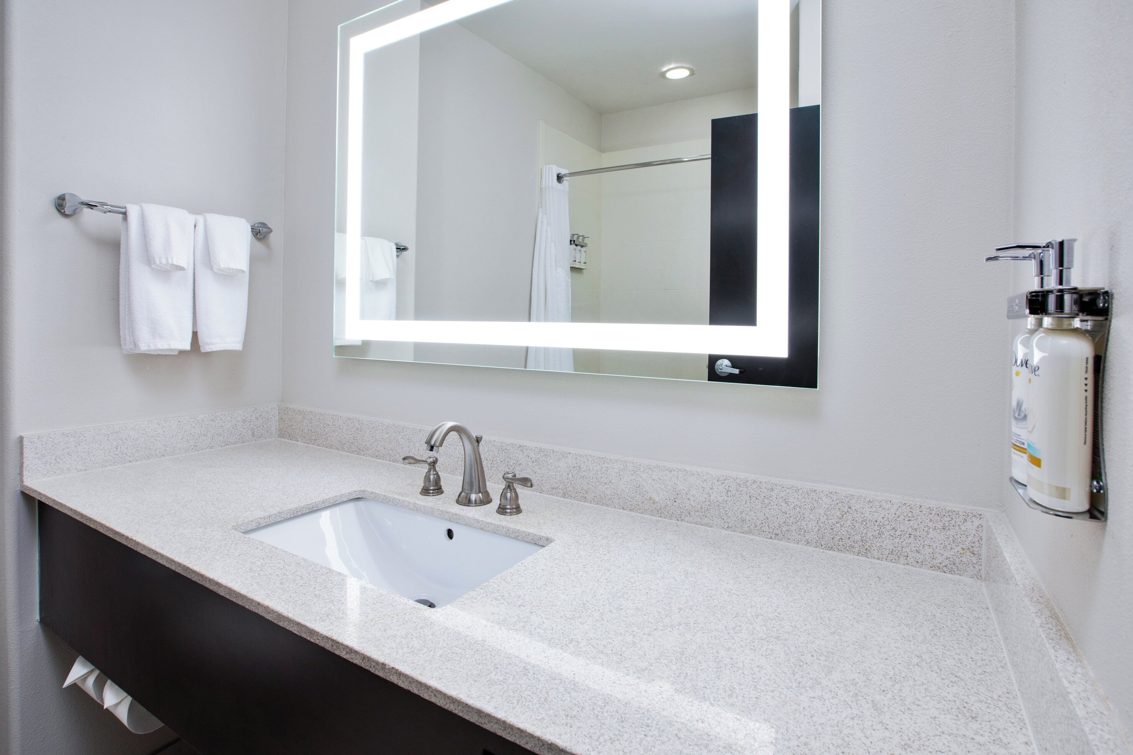 A bathroom with a white sink, a large mirror, and a shower area.