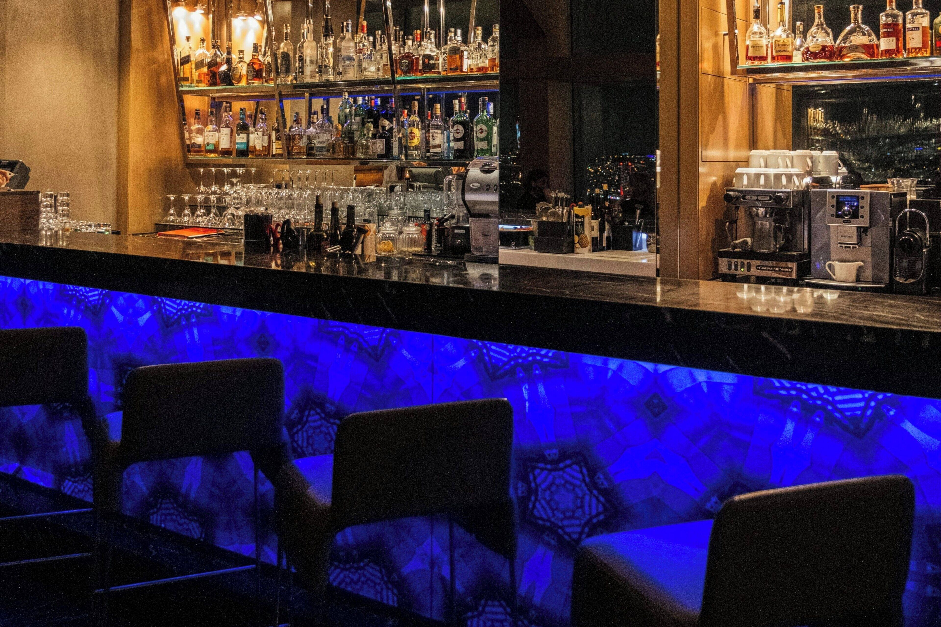 A bar area with a variety of liquor bottles, glasses, and a coffee machine.