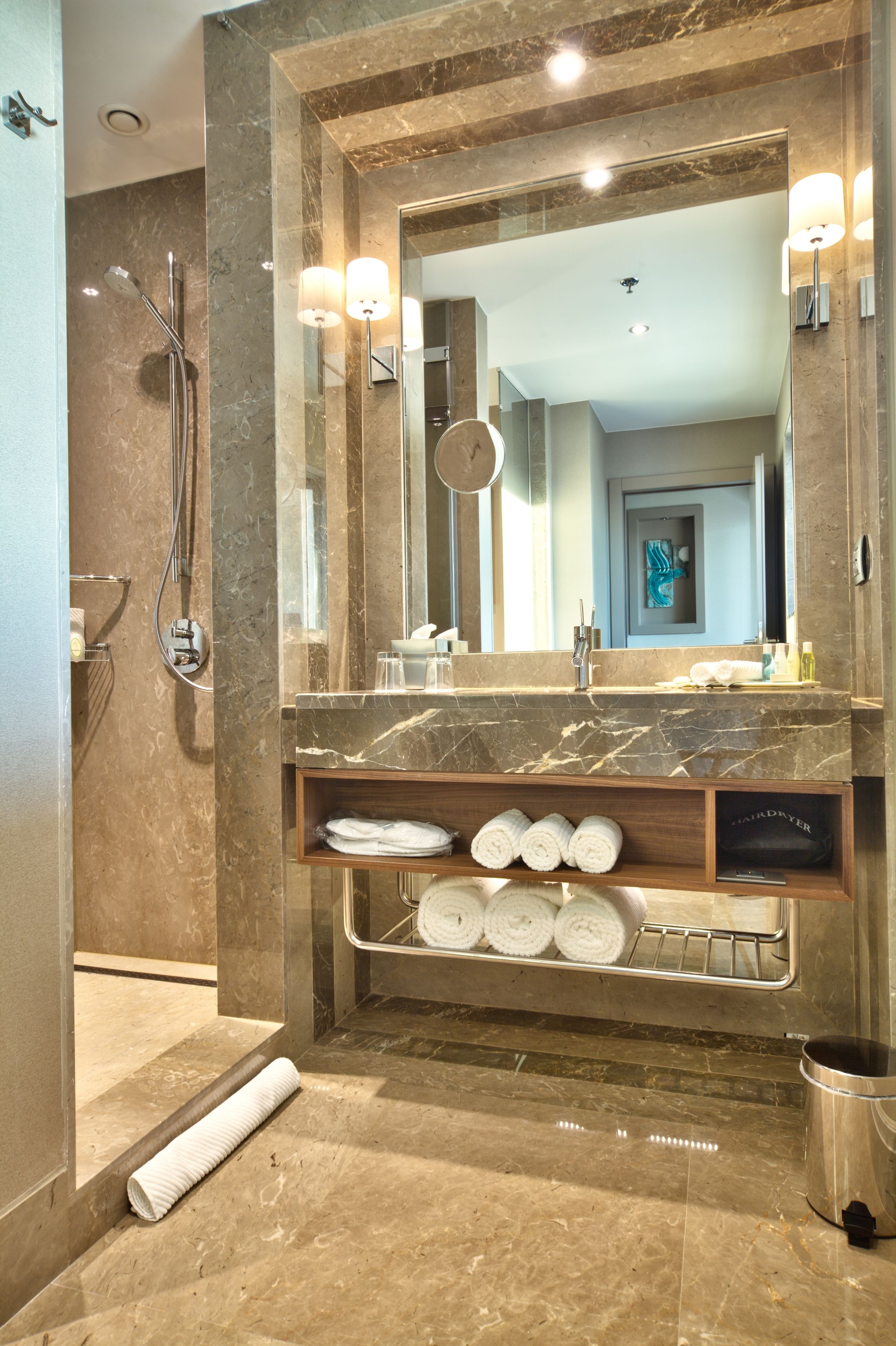 Une salle de bain moderne avec un meuble-lavabo en marbre, un grand miroir et un espace douche.
