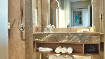 Une salle de bain moderne avec un meuble-lavabo en marbre, un grand miroir et un espace douche.