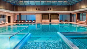 A large indoor swimming pool with a glass ceiling, multiple lanes, and lounge areas with chairs and sun loungers. - Renaissance Istanbul Polat Bosphorus Hotel (Istanbul)