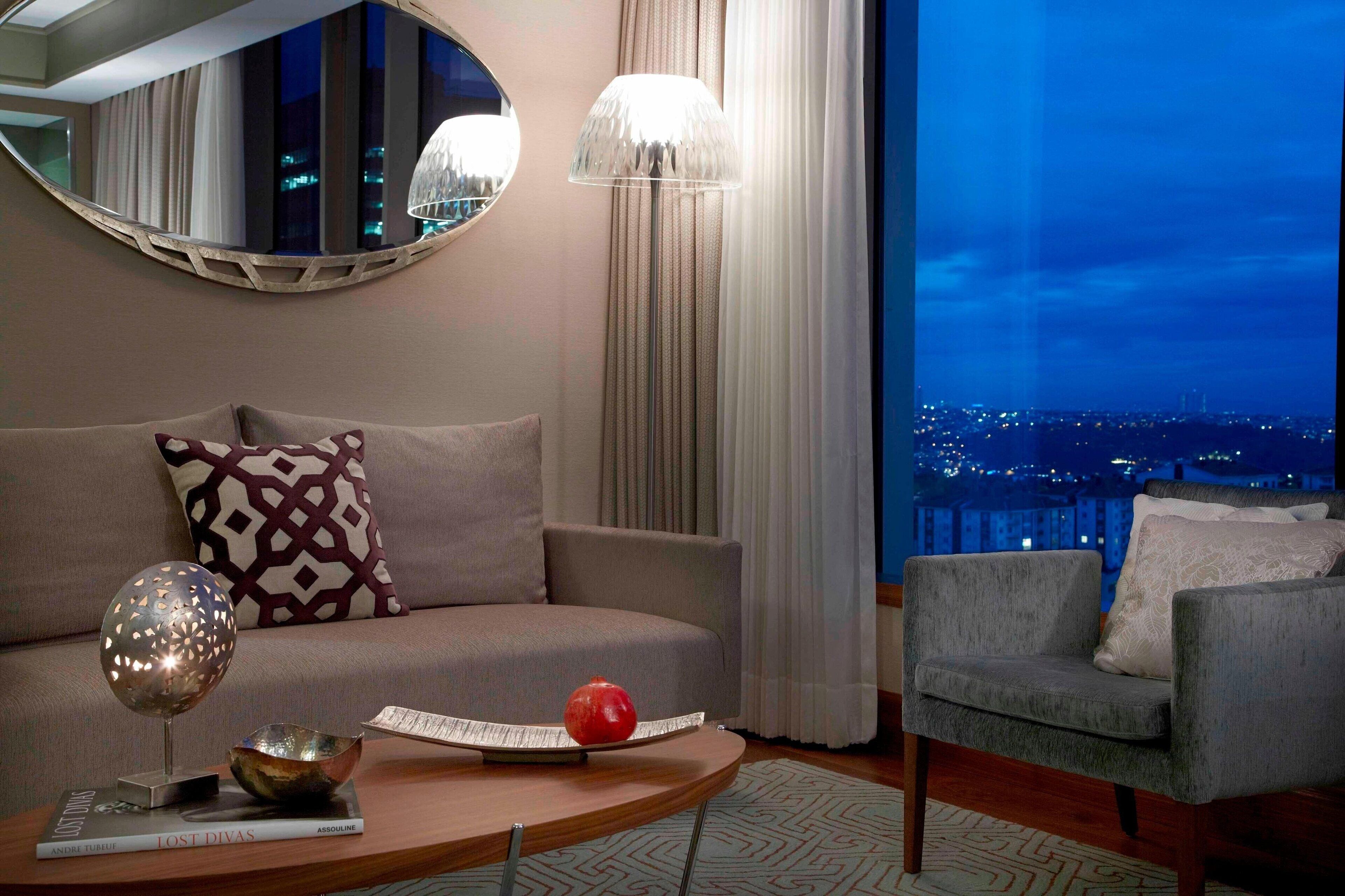Una sala de estar moderna con sofá, sillón y una mesa redonda de centro con un libro y un cuenco decorativo.