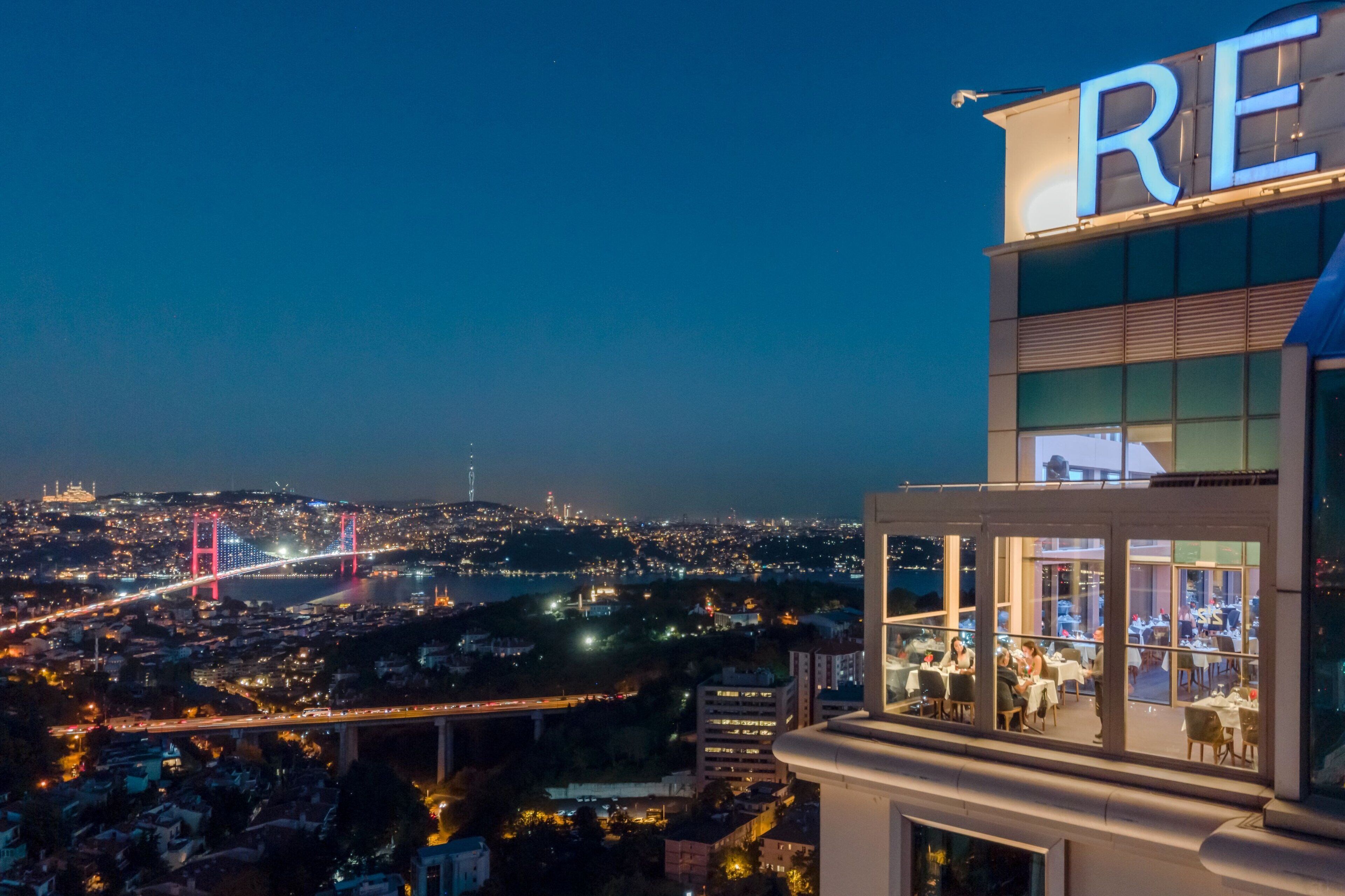 Un hotel con vistas a un paisaje urbano y un puente de noche.