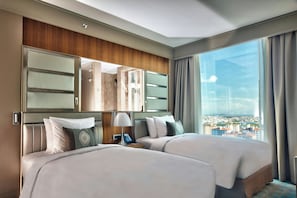 A hotel room with two beds, a large mirror, a bedside table with a lamp, and a view of a cityscape through a large window. - Renaissance Istanbul Polat Bosphorus Hotel (Istanbul)