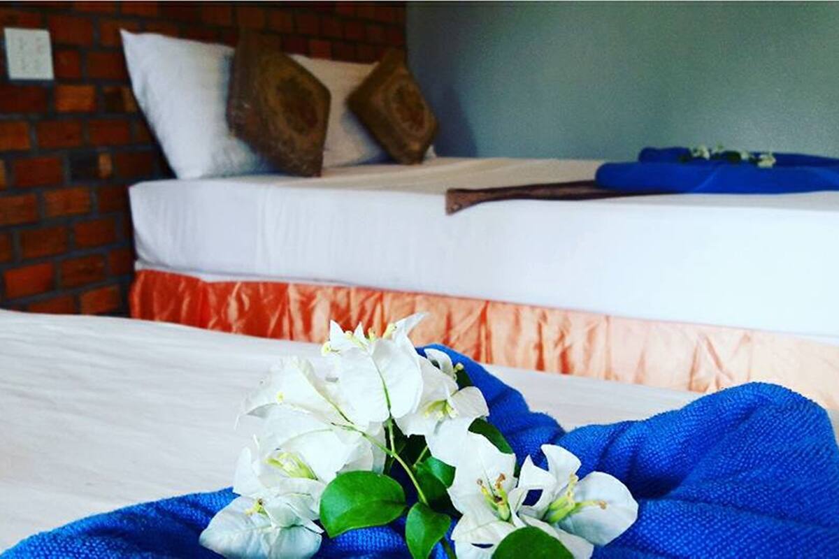 Une chambre d’hôtel avec un lit, un mur en briques et une couverture bleue ornée de fleurs blanches.