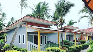 Fileira de casas de dois andares com uma escadaria central, cercada por vegetação exuberante e palmeiras.