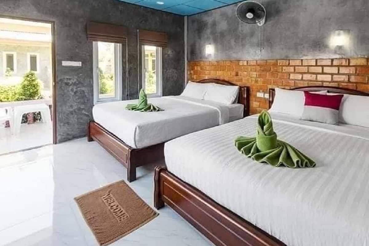 Une chambre d’hôtel avec deux lits, un mur décoratif en briques et une grande fenêtre.