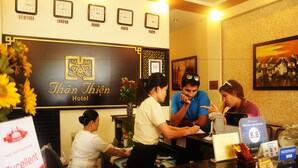 A hotel reception desk with clocks indicating different cities, a framed picture on the wall, and a sign for the 2015 Award. - Than Thien Friendly Hotel (Hue)