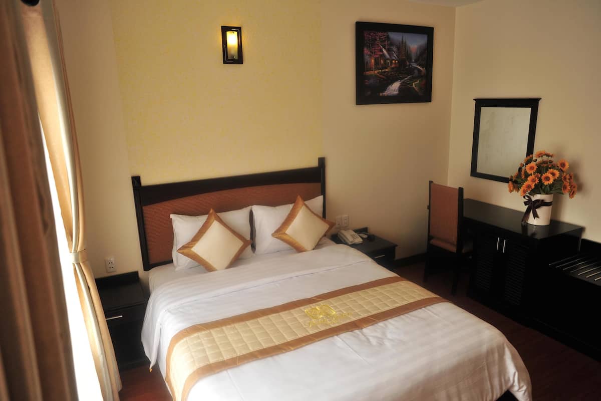 Una habitación de hotel con cama, mesita de noche, cómoda y espejo instalado en la pared.