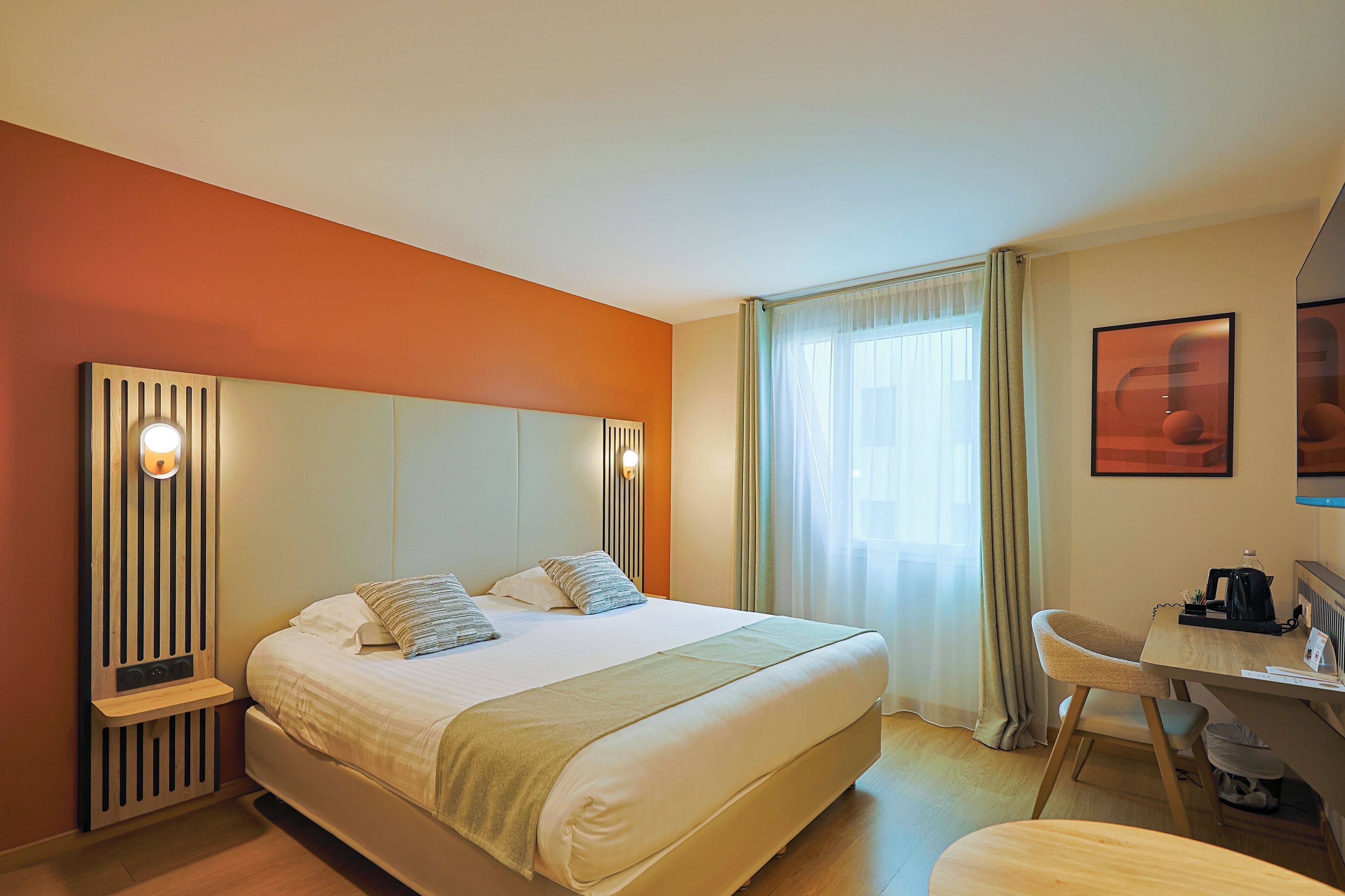 A hotel room with a large bed, a desk, and a chair.