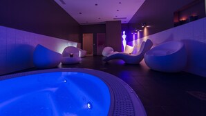 A modern spa area with a heated pool, lounge chairs, and ambient lighting. - Seven Urban Suites Nantes Centre (Nantes)